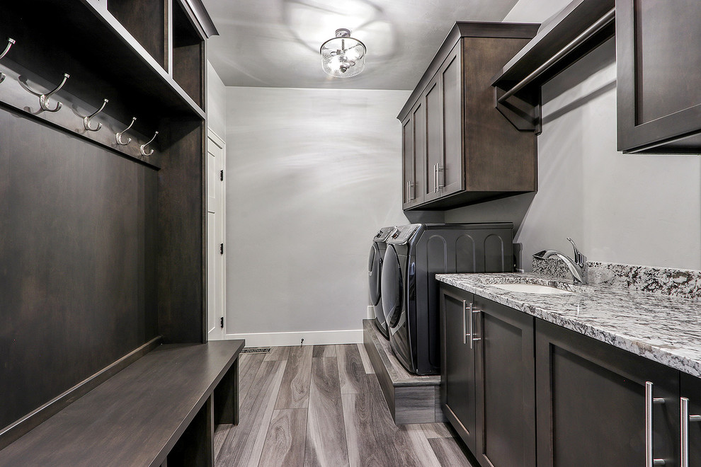 Inspiration for a modern galley utility room in Other with an undermount sink, shaker cabinets, grey cabinets, granite benchtops, grey walls, vinyl floors, a side-by-side washer and dryer and multi-coloured benchtop.