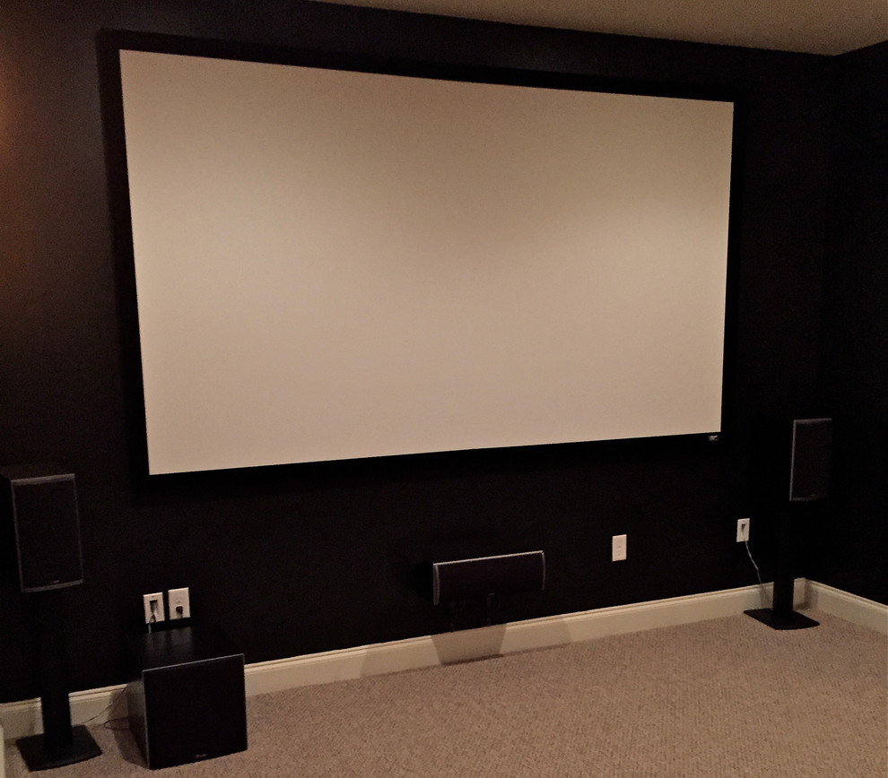 Photo of a large contemporary enclosed home theatre in Philadelphia with carpet, a projector screen and black walls.