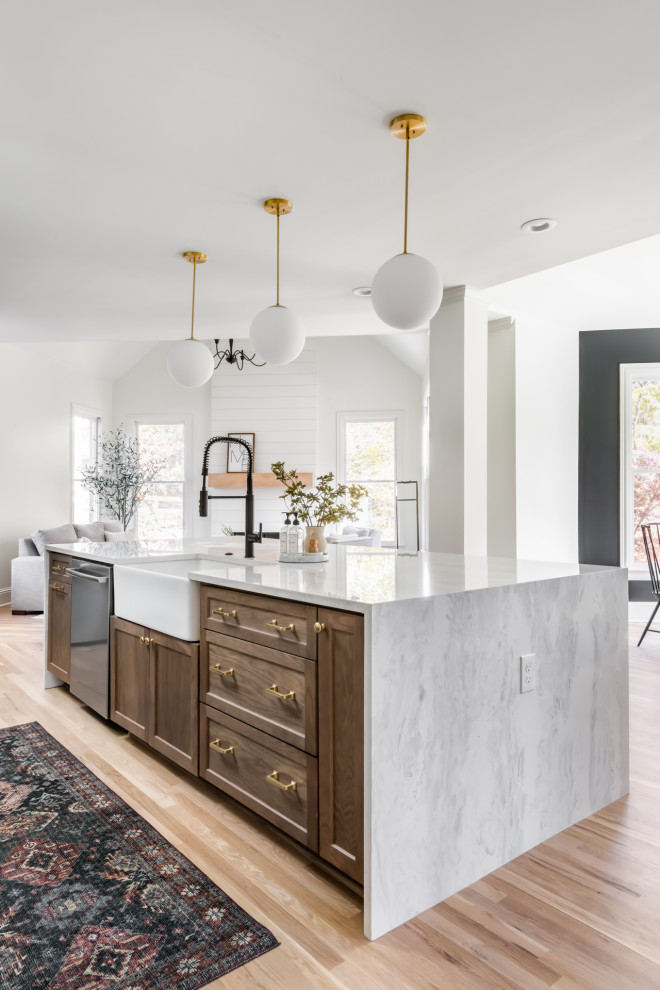 Large transitional single-wall open plan kitchen in Atlanta with a farmhouse sink, shaker cabinets, green cabinets, quartzite benchtops, white splashback, engineered quartz splashback, stainless steel appliances, light hardwood floors, with island and white benchtop.