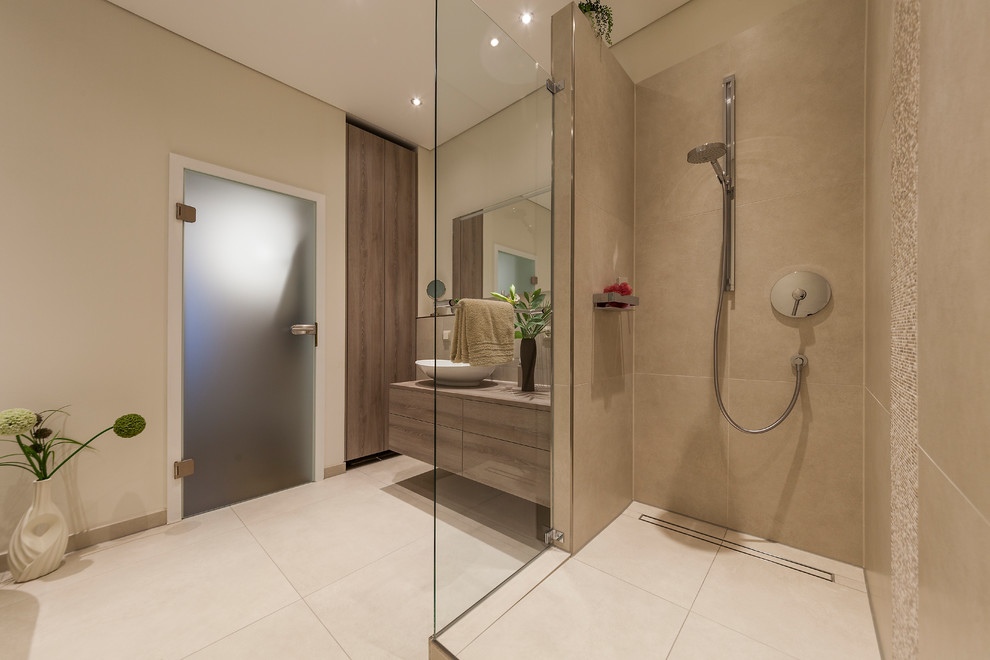 Design ideas for a medium sized contemporary shower room bathroom in Cologne with flat-panel cabinets, brown cabinets, a freestanding bath, a walk-in shower, a two-piece toilet, beige tiles, stone tiles, beige walls, a vessel sink, solid surface worktops, beige floors and an open shower.
