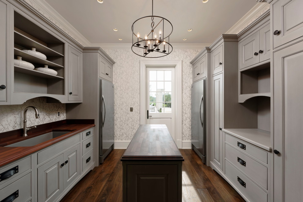 Expansive traditional galley utility room in DC Metro with beaded inset cabinets, grey cabinets, wood benchtops, dark hardwood floors, a side-by-side washer and dryer, brown floor, an undermount sink and white walls.