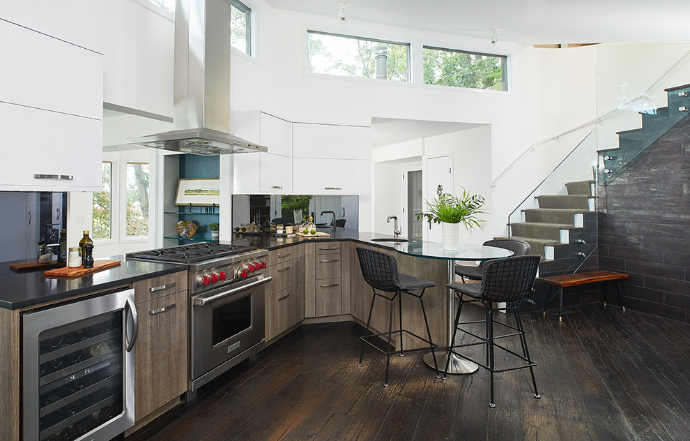 Mountain style dark wood floor and brown floor open concept kitchen photo with a single-bowl sink, flat-panel cabinets, white cabinets, mirror backsplash, stainless steel appliances, a peninsula and black countertops