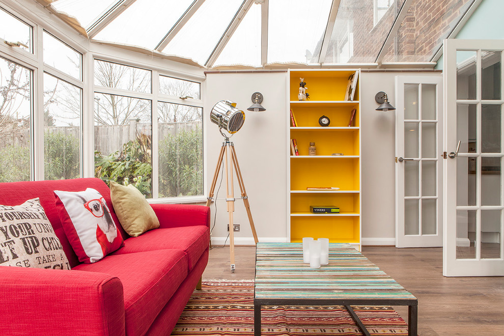 This is an example of an eclectic sunroom in London with medium hardwood floors and a glass ceiling.