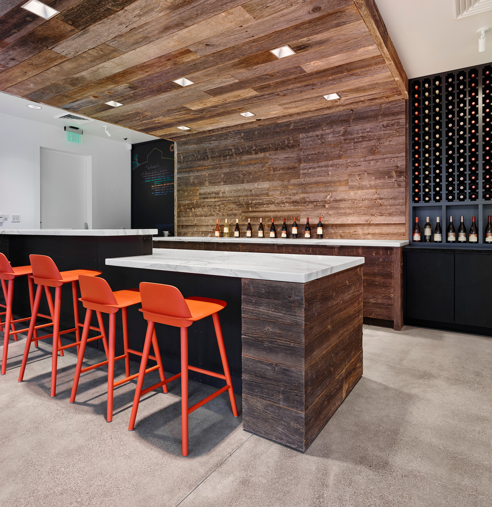 Photo of a mid-sized contemporary u-shaped seated home bar in San Francisco with flat-panel cabinets, dark wood cabinets, marble benchtops, brown splashback, timber splashback and concrete floors.