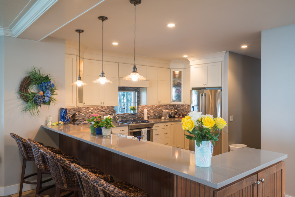 This is an example of a large country u-shaped eat-in kitchen in Providence with multi-coloured splashback, stone tile splashback, stainless steel appliances and a peninsula.