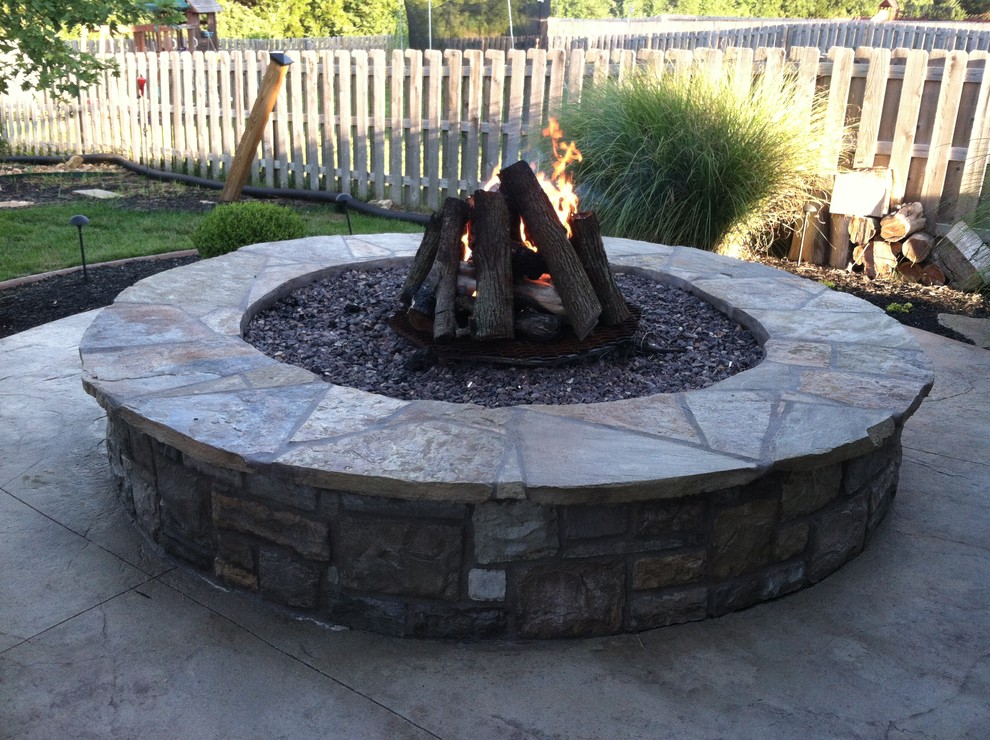 This is an example of a large traditional backyard patio in Kansas City with a fire feature, concrete pavers and no cover.