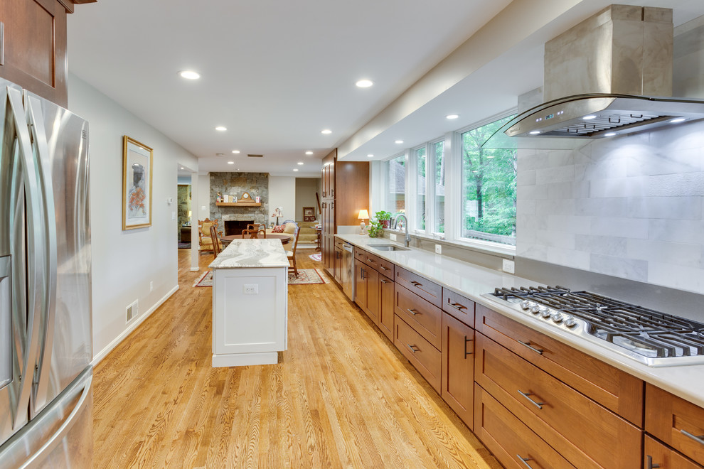 Large transitional galley kitchen in DC Metro with shaker cabinets, quartz benchtops, stainless steel appliances, medium hardwood floors and multiple islands.