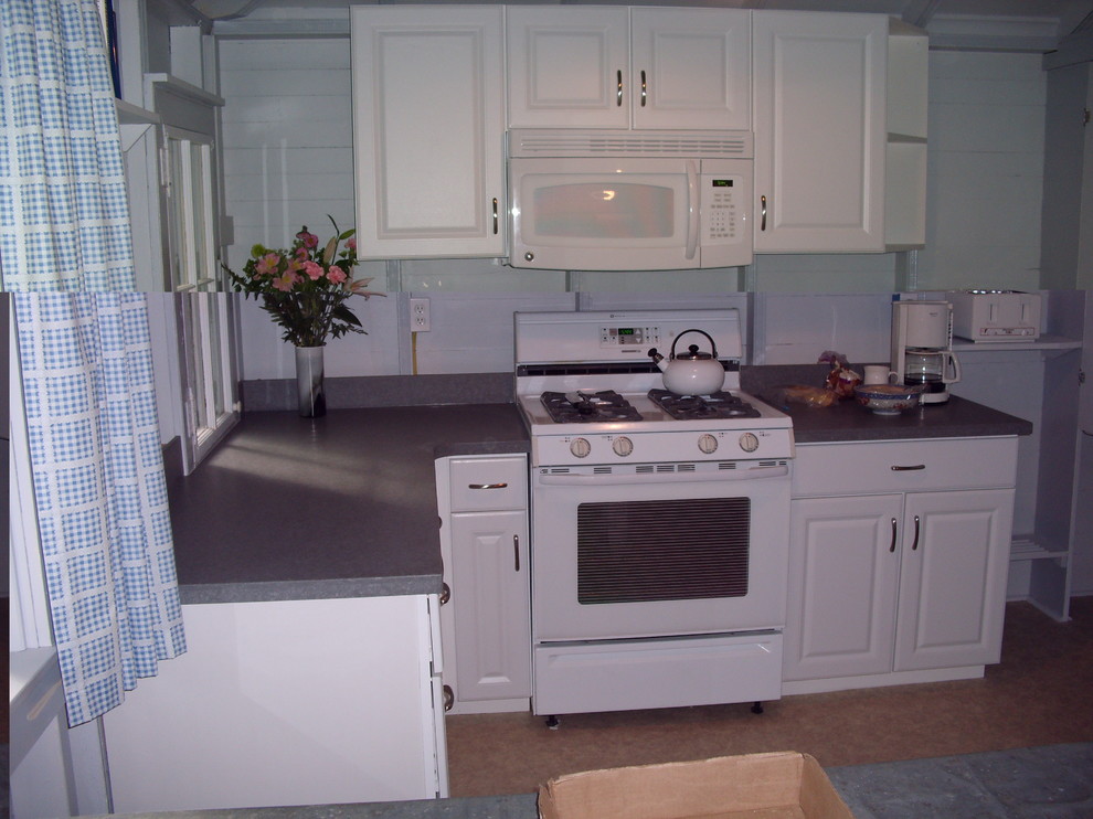 Small vinyl floor eat-in kitchen photo with raised-panel cabinets, laminate countertops and white appliances