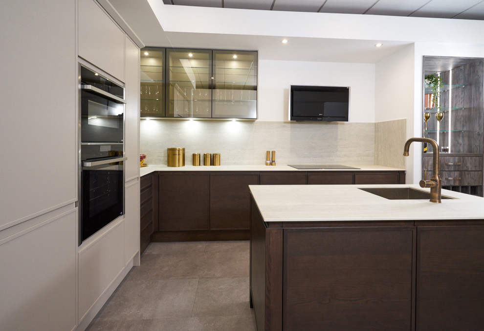 This is an example of a medium sized modern l-shaped kitchen/diner in Cheshire with a built-in sink, flat-panel cabinets, dark wood cabinets, engineered stone countertops, beige splashback, integrated appliances, lino flooring, an island, grey floors and white worktops.