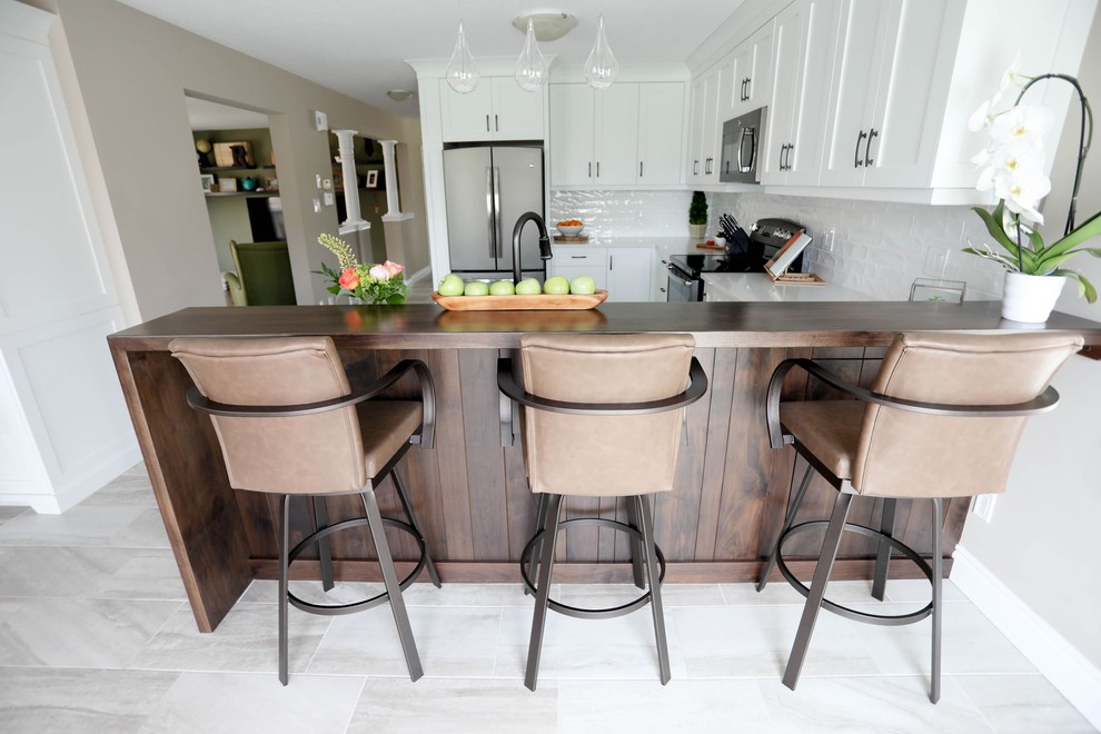 Inspiration for a mid-sized transitional u-shaped porcelain tile and gray floor open concept kitchen remodel with shaker cabinets, white cabinets, quartz countertops, white backsplash, ceramic backsplash, stainless steel appliances, a peninsula, white countertops and a double-bowl sink