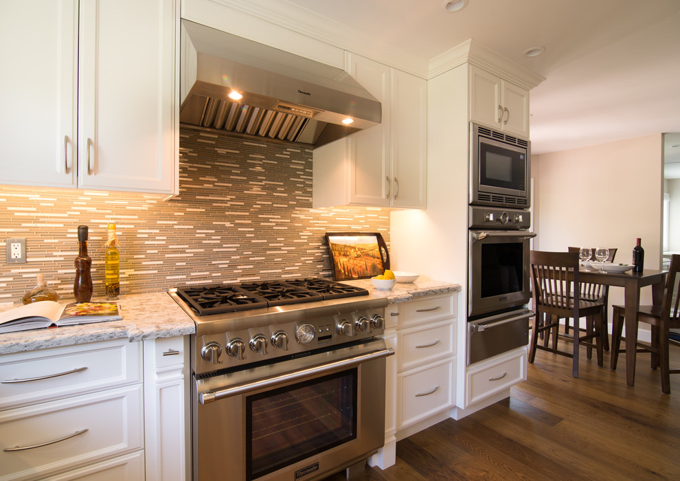 Eat-in kitchen - mid-sized transitional u-shaped dark wood floor eat-in kitchen idea in Los Angeles with an undermount sink, raised-panel cabinets, white cabinets, granite countertops, gray backsplash, matchstick tile backsplash and stainless steel appliances