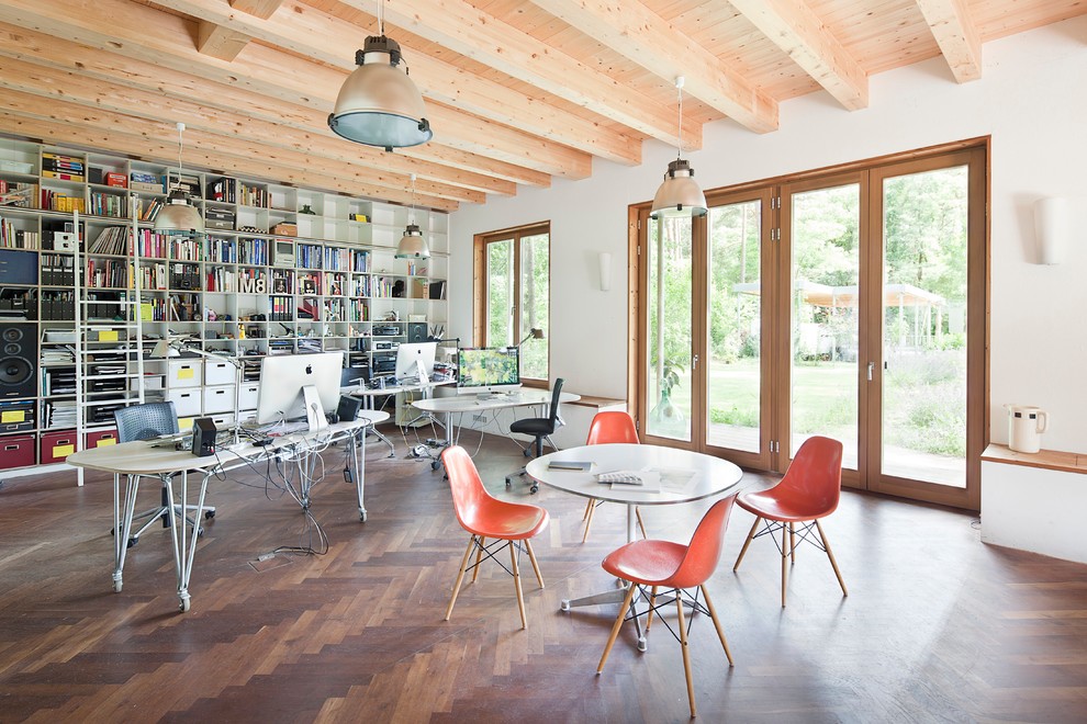This is an example of an expansive scandinavian study room in Berlin with medium hardwood floors, a freestanding desk, white walls, no fireplace and brown floor.