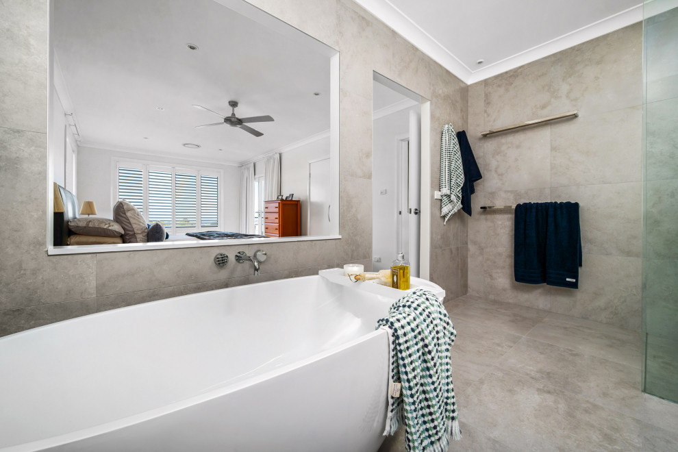 This is an example of a mid-sized beach style 3/4 bathroom in Newcastle - Maitland with flat-panel cabinets, blue cabinets, a freestanding tub, an open shower, a two-piece toilet, white tile, grey walls, an integrated sink, grey floor, an open shower, white benchtops, a single vanity and a floating vanity.