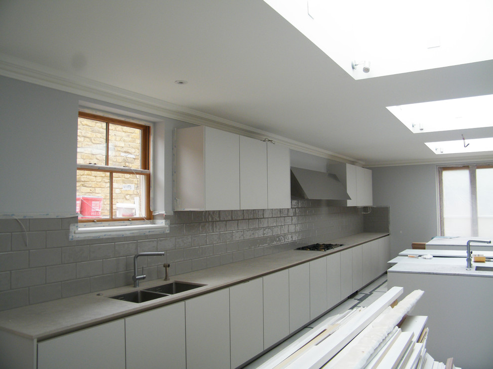 Design ideas for a large modern galley separate kitchen in London with an undermount sink, flat-panel cabinets, grey cabinets, quartz benchtops, grey splashback, ceramic splashback, stainless steel appliances, porcelain floors, multiple islands and pink benchtop.