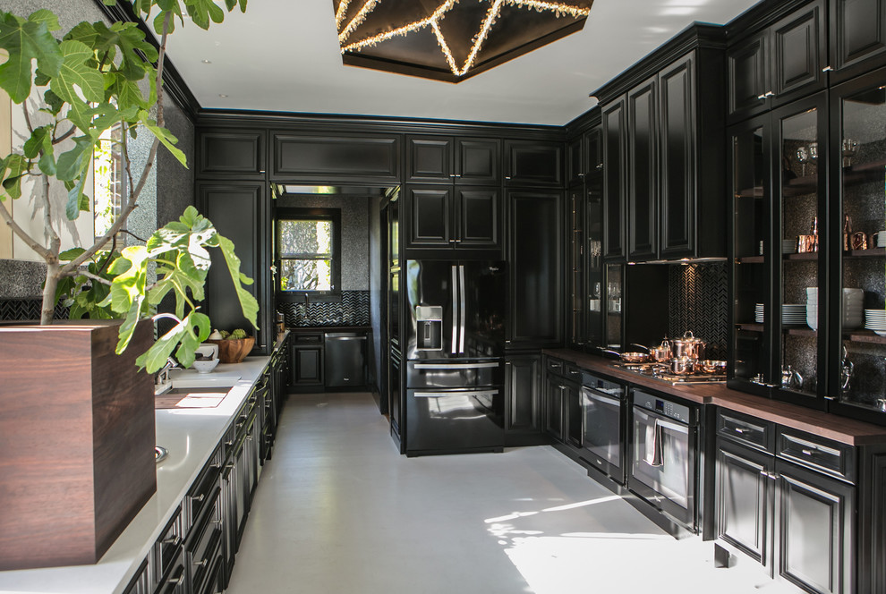 Photo of a large modern galley separate kitchen in San Francisco with a double-bowl sink, black cabinets, quartzite benchtops, metallic splashback, ceramic splashback, black appliances, slate floors and raised-panel cabinets.