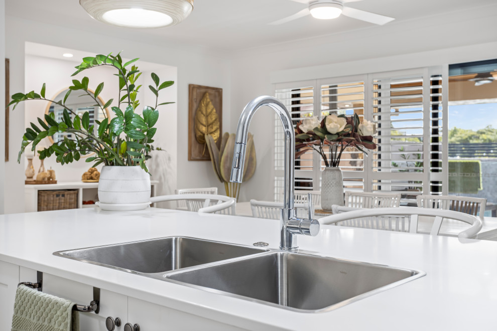 Inspiration for a mid-sized contemporary galley eat-in kitchen in Gold Coast - Tweed with an undermount sink, shaker cabinets, white cabinets, quartz benchtops, white splashback, engineered quartz splashback, stainless steel appliances, ceramic floors, with island, beige floor and white benchtop.