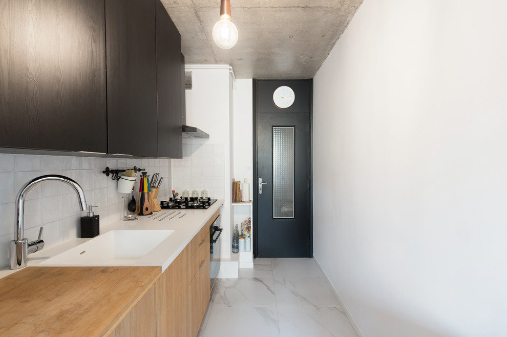 This is an example of a mid-sized contemporary single-wall separate kitchen in Toulouse with an integrated sink, medium wood cabinets, wood benchtops, white splashback, ceramic splashback, panelled appliances, no island, beige benchtop, glass-front cabinets, light hardwood floors and beige floor.