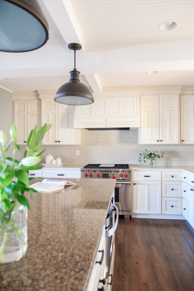 Example of a transitional l-shaped vinyl floor kitchen design in Minneapolis with an undermount sink, raised-panel cabinets, white cabinets, quartz countertops, beige backsplash, ceramic backsplash, paneled appliances and an island