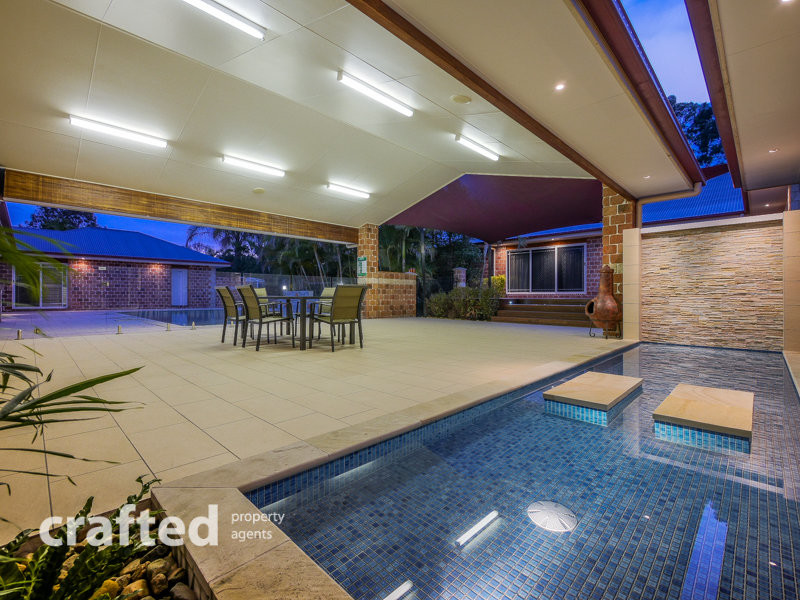 Photo of an expansive modern courtyard rectangular lap pool in Brisbane with a water feature and natural stone pavers.