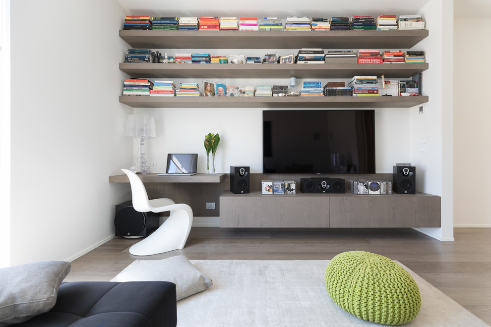 This is an example of a contemporary family room in Rome with a library, white walls, light hardwood floors, a wall-mounted tv and beige floor.