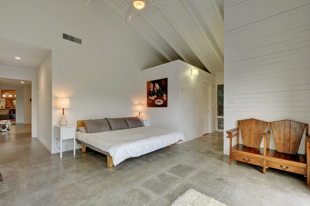 This is an example of a mid-sized eclectic master bedroom in Austin with white walls, concrete floors and no fireplace.