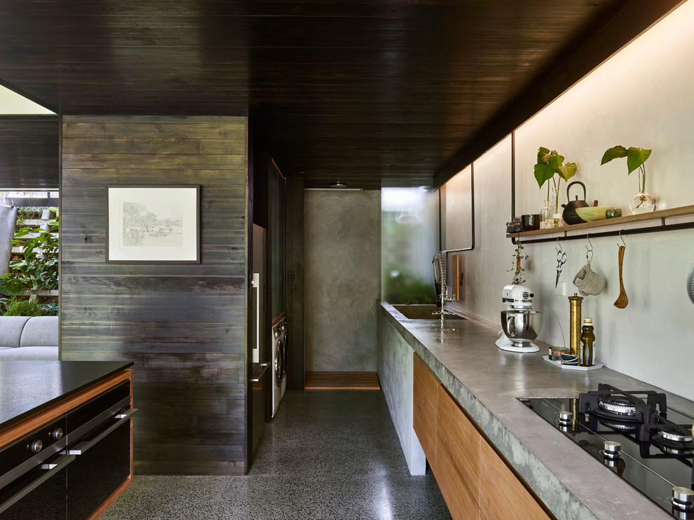Small modern galley kitchen pantry in Brisbane with an undermount sink, flat-panel cabinets, light wood cabinets, white splashback, black appliances, concrete floors, with island, grey floor and concrete benchtops.