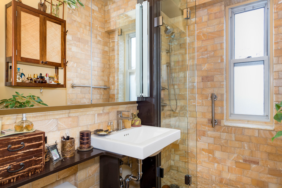 Photo of a small mediterranean bathroom in New York with an alcove shower, a two-piece toilet, stone tile, multi-coloured walls, ceramic floors, a wall-mount sink and beige tile.