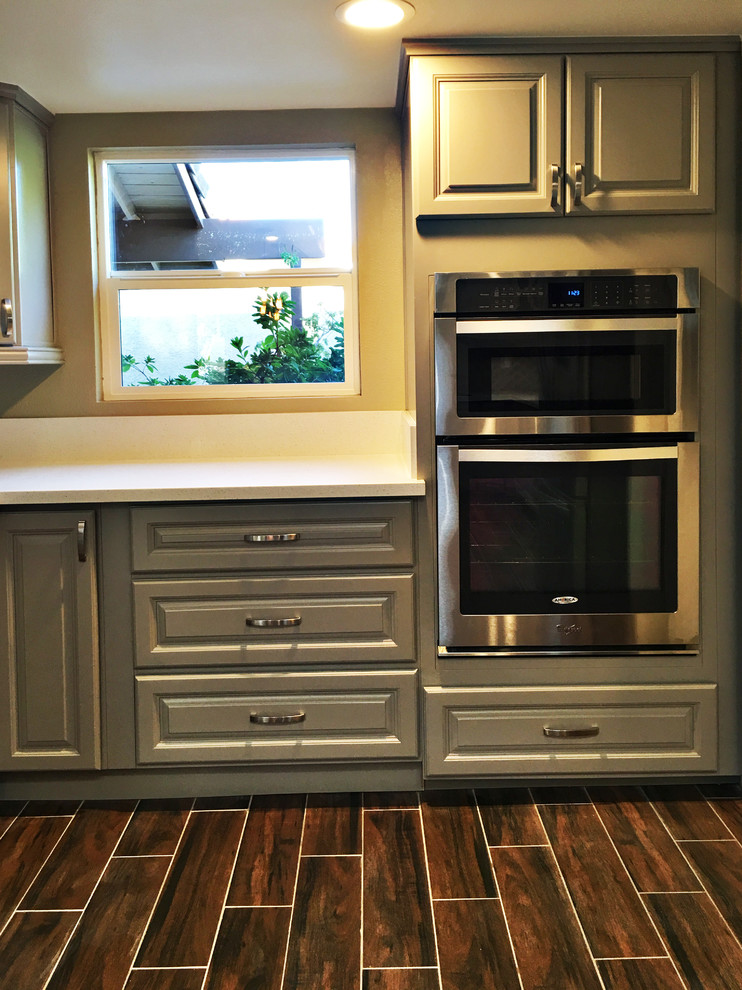Eat-in kitchen - mid-sized transitional u-shaped medium tone wood floor eat-in kitchen idea in Orange County with raised-panel cabinets, gray cabinets, quartz countertops, a peninsula, a double-bowl sink, brown backsplash, mosaic tile backsplash and stainless steel appliances