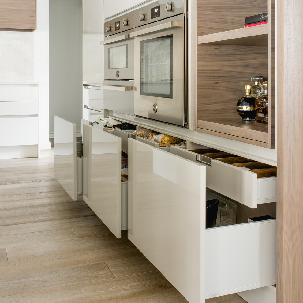 Design ideas for a mid-sized contemporary l-shaped eat-in kitchen in Dallas with an undermount sink, flat-panel cabinets, white cabinets, quartz benchtops, white splashback, stone slab splashback, stainless steel appliances and light hardwood floors.
