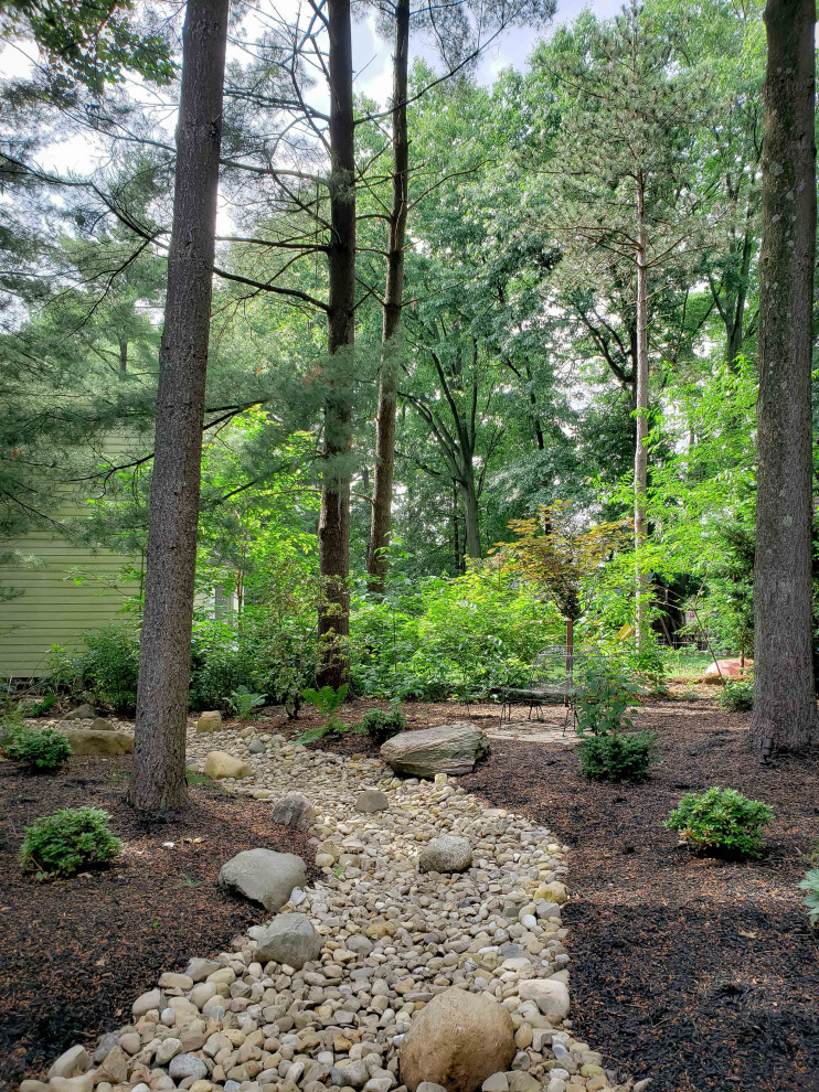 This is an example of a large backyard garden in Columbus with a garden path and river rock.