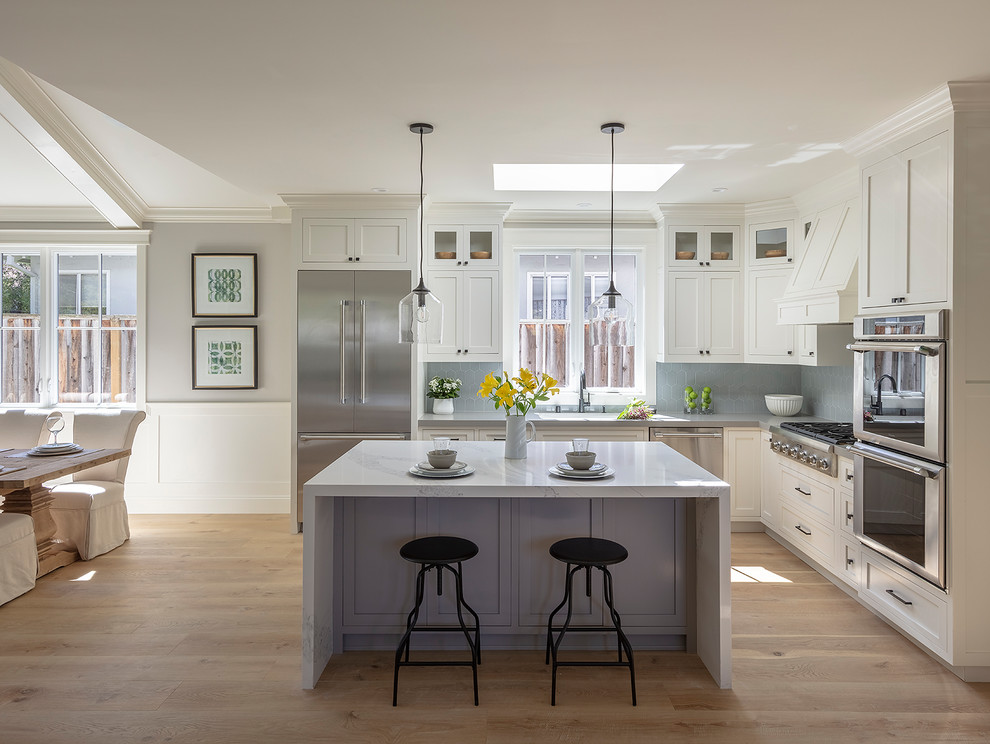 Design ideas for a small country l-shaped open plan kitchen in San Francisco with an undermount sink, shaker cabinets, white cabinets, quartz benchtops, blue splashback, ceramic splashback, stainless steel appliances, light hardwood floors, with island, beige floor and white benchtop.