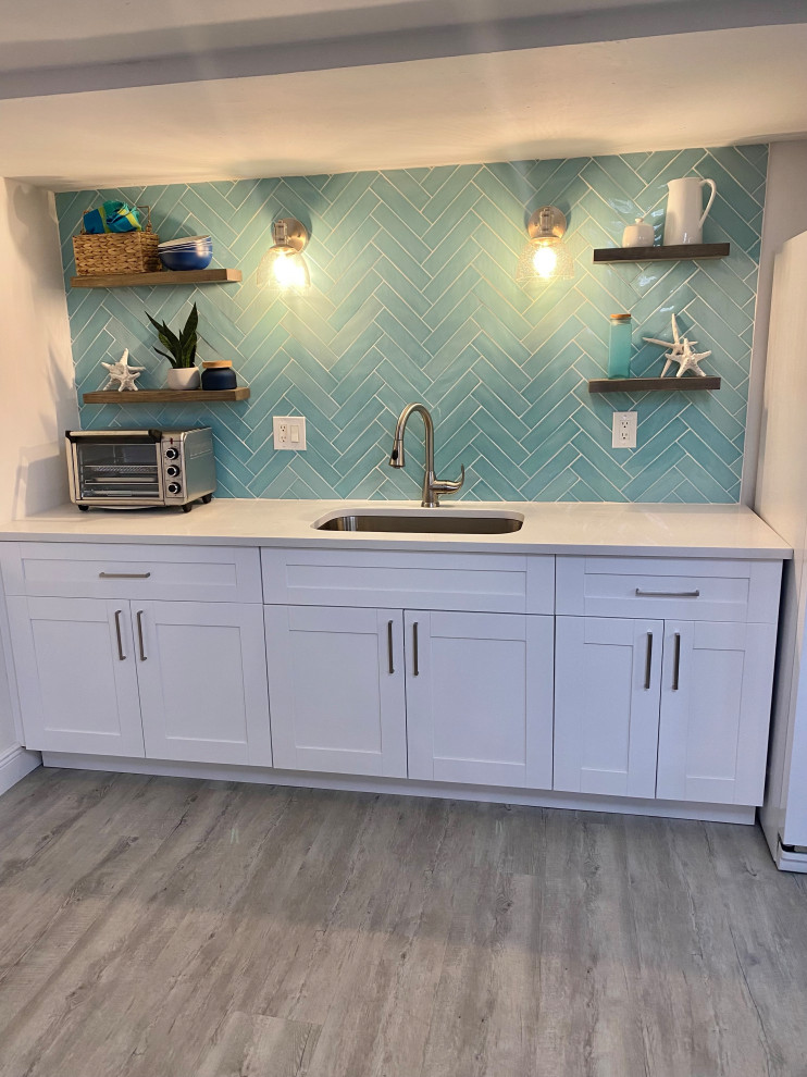 Photo of a nautical kitchen in Other with shaker cabinets, white cabinets, quartz worktops, blue splashback, glass tiled splashback, porcelain flooring and white worktops.
