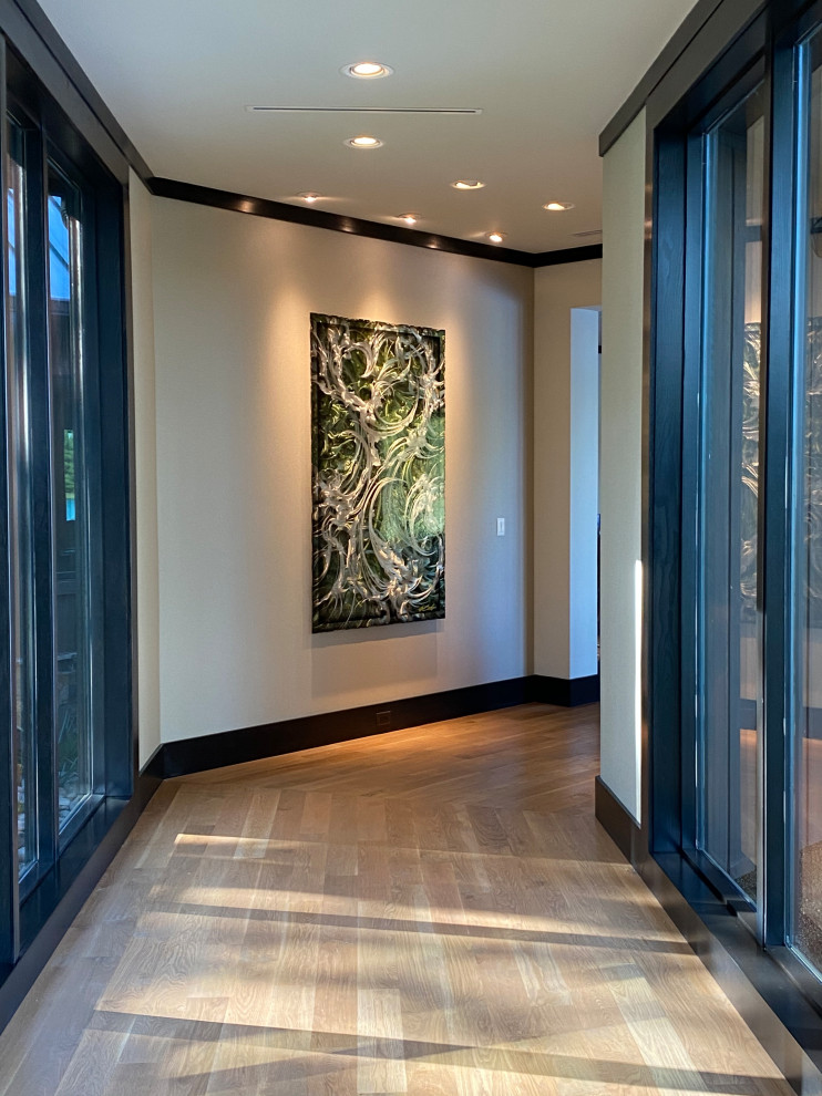 広いトランジショナルスタイルのおしゃれな廊下 (ベージュの壁、淡色無垢フローリング、茶色い床、ベージュの天井) の写真