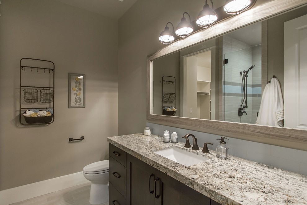 Photo of a large country 3/4 bathroom in Salt Lake City with an undermount sink, recessed-panel cabinets, dark wood cabinets, granite benchtops, an alcove shower, beige tile, ceramic tile, grey walls and ceramic floors.