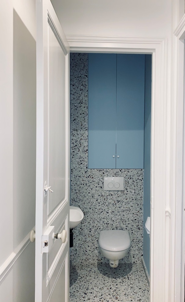 Exempel på ett modernt toalett, med luckor med infälld panel, en vägghängd toalettstol, vita väggar, ett väggmonterat handfat och flerfärgat golv