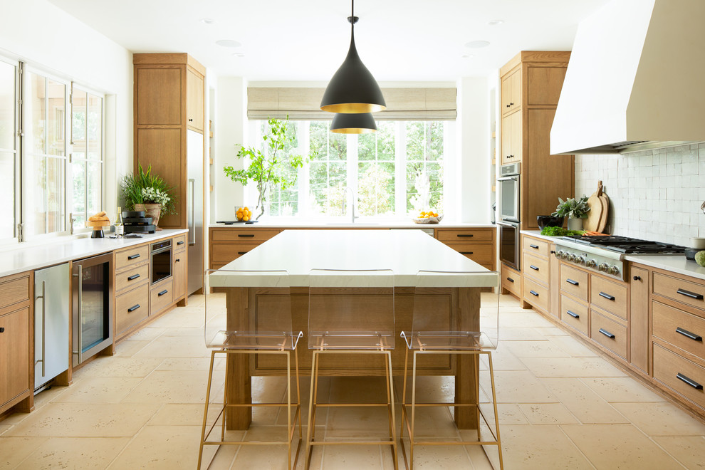 Inspiration for a mediterranean u-shaped kitchen in Atlanta with beaded inset cabinets, medium wood cabinets, white splashback, stainless steel appliances, with island, beige floor and white benchtop.