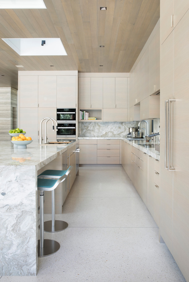 Modern inredning av ett stort grå grått kök, med en undermonterad diskho, släta luckor, skåp i ljust trä, marmorbänkskiva, vitt stänkskydd, stänkskydd i marmor, integrerade vitvaror, terrazzogolv, en köksö och vitt golv