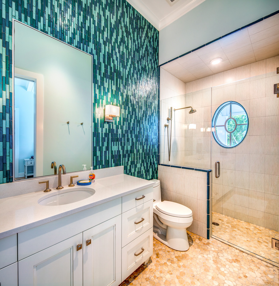 Mid-sized beach style 3/4 bathroom in Tampa with white cabinets, a two-piece toilet, beige walls, an undermount sink, a hinged shower door, white benchtops, recessed-panel cabinets, a curbless shower, blue tile and beige floor.