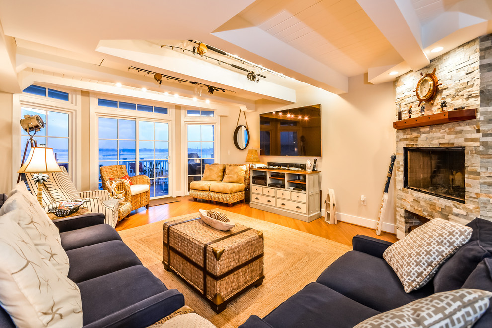 Photo of a large beach style enclosed living room in DC Metro with white walls, medium hardwood floors, a corner fireplace, a stone fireplace surround and a wall-mounted tv.