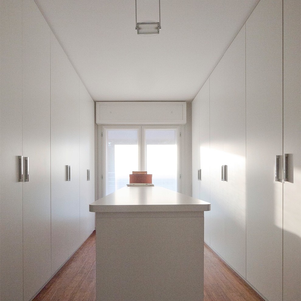 Photo of a large modern gender-neutral built-in wardrobe with flat-panel cabinets, white cabinets and bamboo floors.
