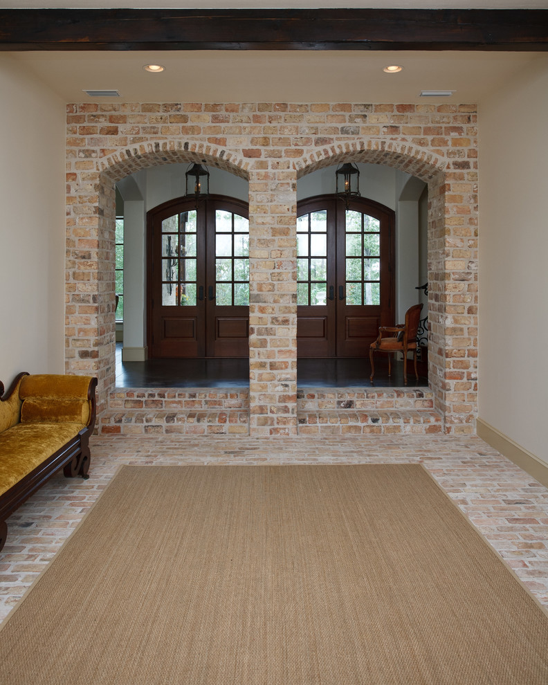 This is an example of a mid-sized traditional entry hall in Little Rock with white walls, brick floors, a double front door, a dark wood front door and beige floor.