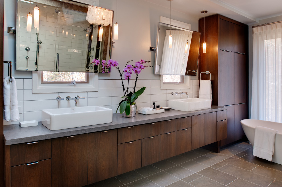 This is an example of a modern master bathroom in Richmond with a vessel sink, flat-panel cabinets, dark wood cabinets, limestone benchtops, a freestanding tub, a wall-mount toilet, white tile, ceramic tile, white walls and slate floors.