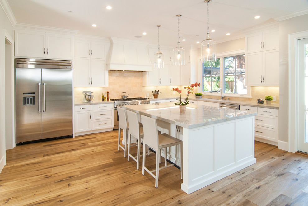 Design ideas for a traditional l-shaped kitchen in San Francisco with an undermount sink, shaker cabinets, white cabinets, beige splashback, stainless steel appliances, light hardwood floors and with island.