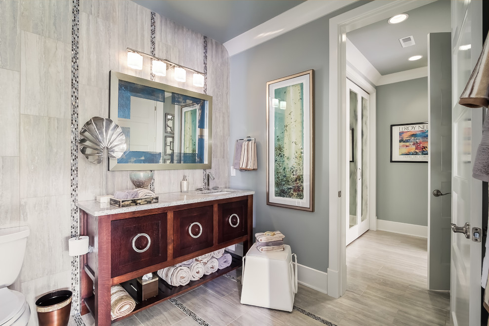 This is an example of a beach style bathroom in Nashville with flat-panel cabinets, medium wood cabinets, granite benchtops, gray tile, porcelain tile, grey walls and ceramic floors.