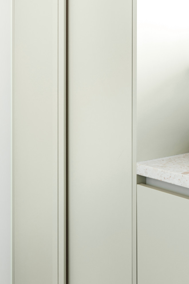 Imagen de lavadero lineal actual de tamaño medio con puertas de armario verdes, encimera de terrazo, salpicadero gris, paredes blancas, lavadora y secadora apiladas y encimeras blancas