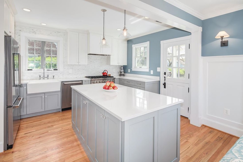 Kitchen - mid-sized cottage u-shaped medium tone wood floor kitchen idea in DC Metro with a farmhouse sink, gray cabinets, quartz countertops, white backsplash, stainless steel appliances and an island