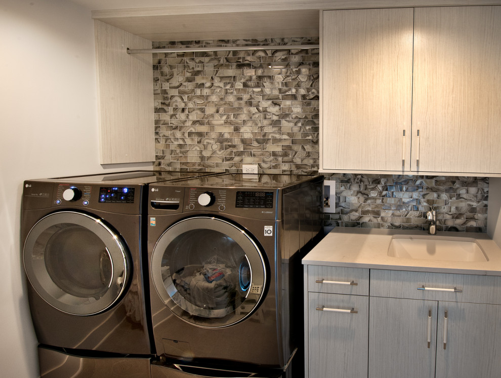 Design ideas for a country laundry room in Chicago with flat-panel cabinets, grey cabinets, concrete benchtops, grey splashback, glass tile splashback, a side-by-side washer and dryer and grey benchtop.