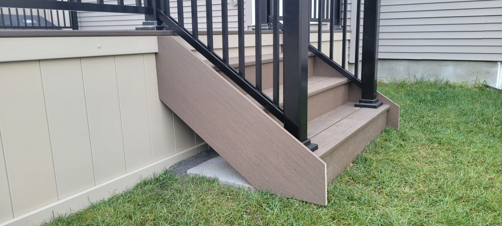 This is an example of a large modern backyard and ground level deck in Ottawa with with skirting, no cover and metal railing.