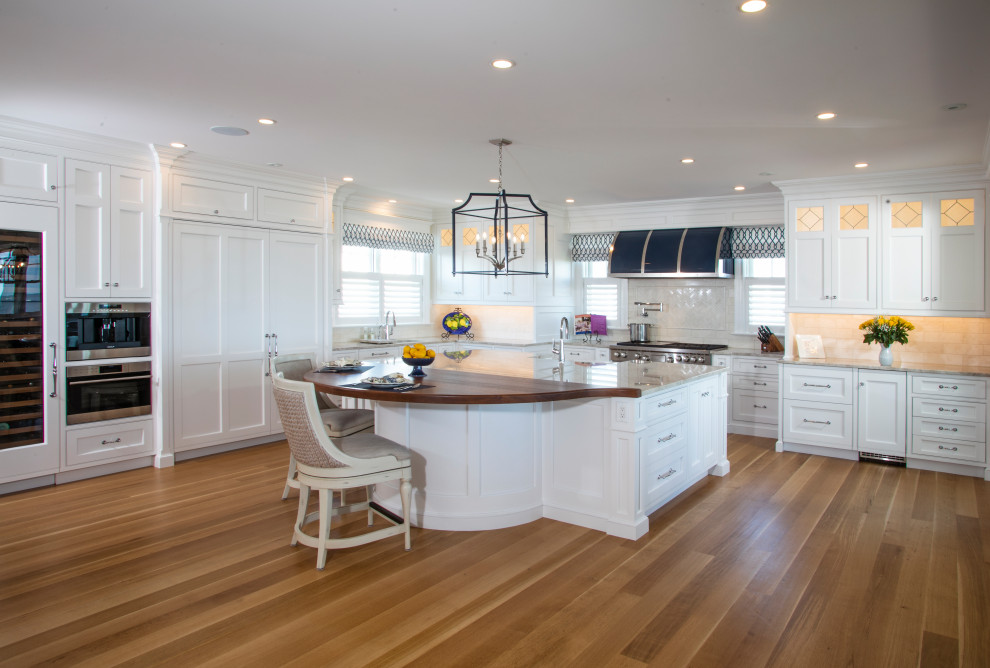 Inspiration for a beach style l-shaped kitchen in Philadelphia with shaker cabinets, white cabinets, grey splashback, panelled appliances, light hardwood floors, with island and grey benchtop.