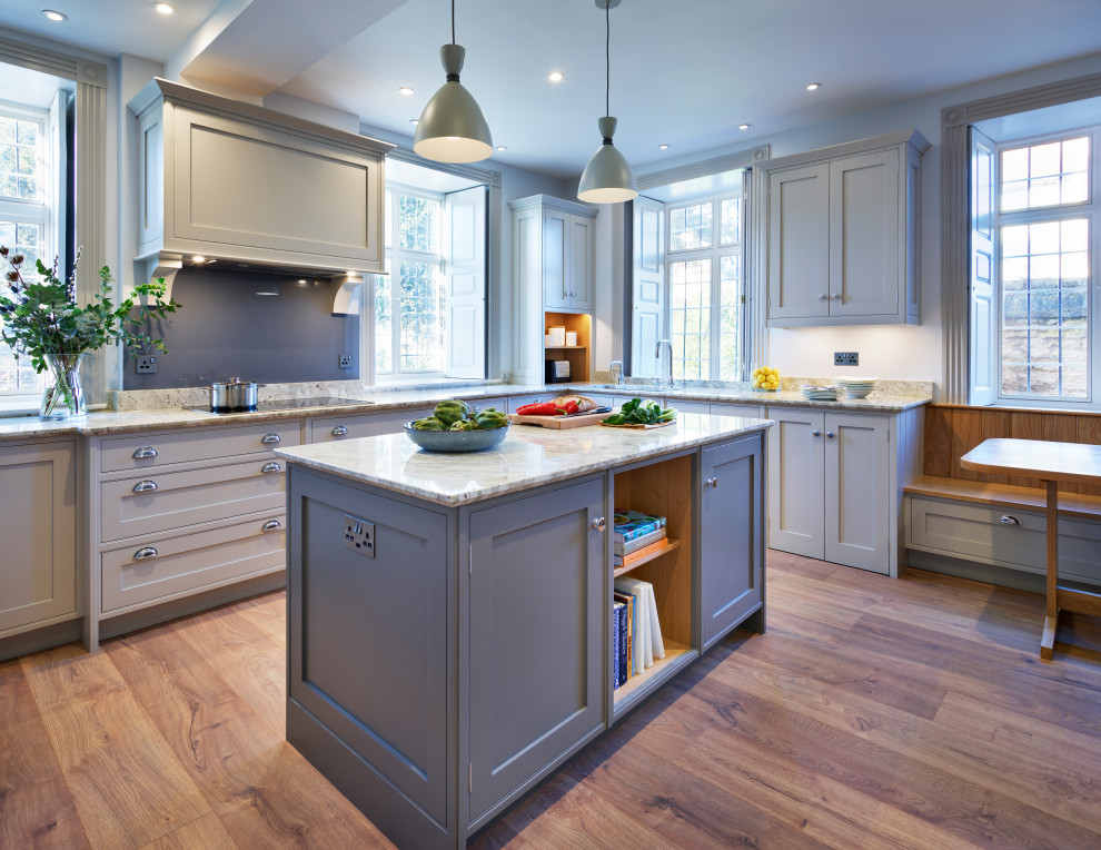 This is an example of a large traditional eat-in kitchen in Buckinghamshire with an integrated sink, shaker cabinets, granite benchtops, grey splashback, black appliances, with island and white benchtop.